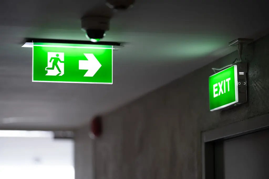 Commercial building emergency exit door with illuminated exit sign and emergency lighting system in Nisku, Alberta.