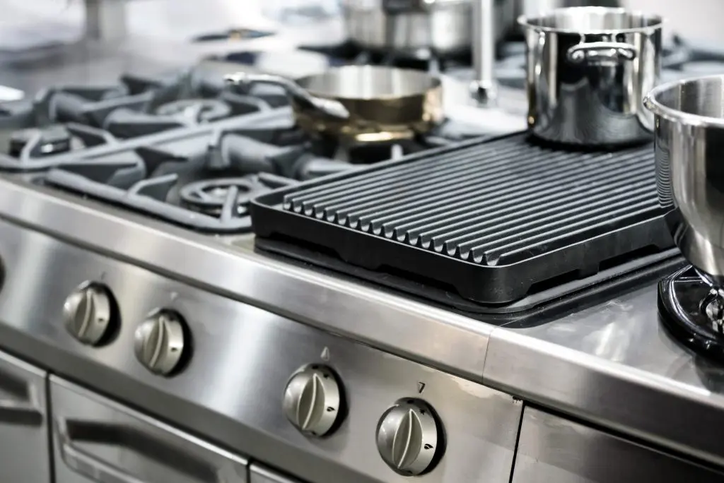 Commercial kitchen cooking equipment protected by fire suppression system
