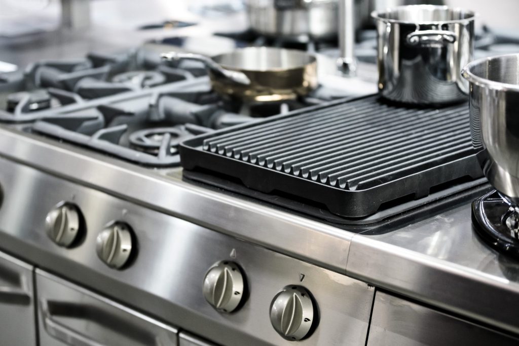 Commercial kitchen cooking equipment protected by fire suppression system